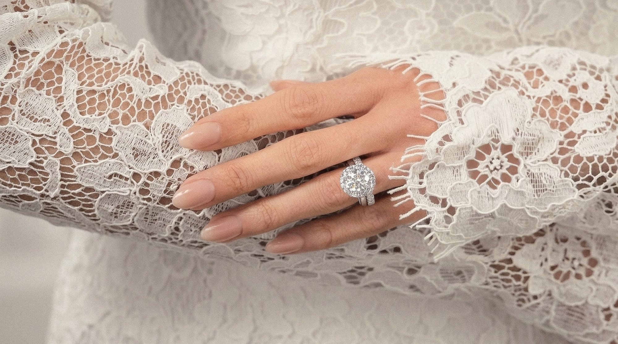 A close up of a hand wearing a diamond engagement ring stacked with a matching wedding band to illustrate how they differ in design and purpose